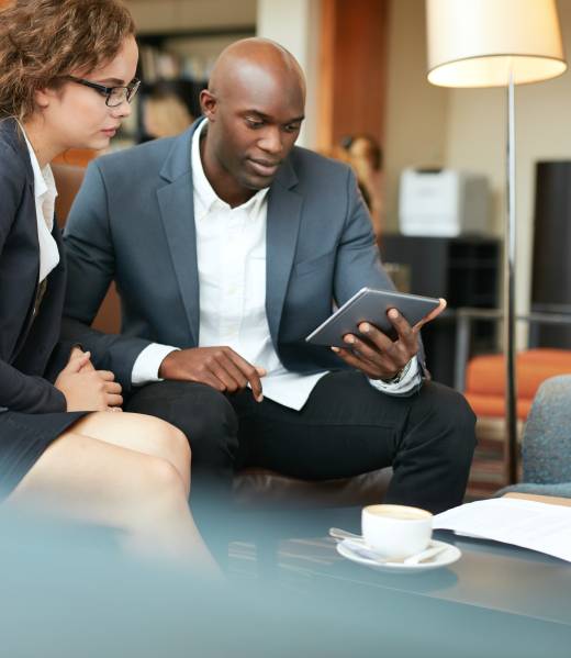 Businessman showing reports to businesswoman on digital tablet. Business people meeting in a coffee shop.
