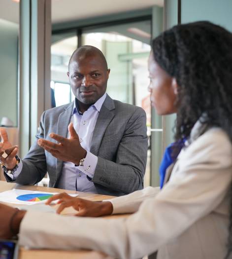 Image of young businessmen and colleague discussing document in laptop and touchpad at meeting